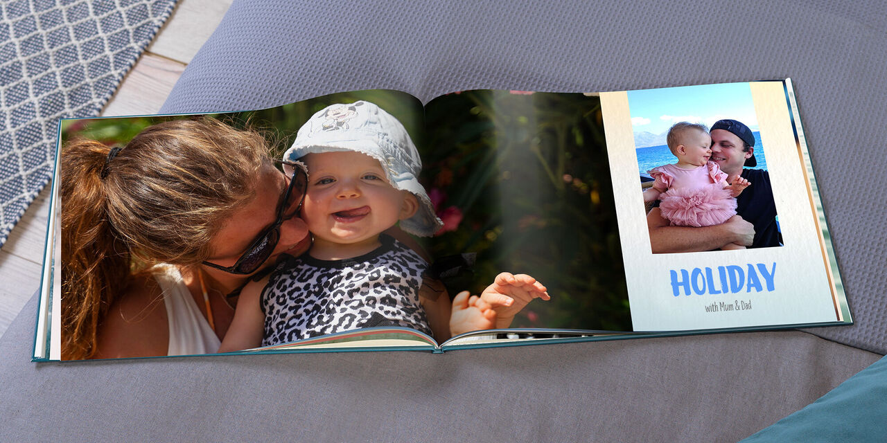 An open CEWE PHOTOBOOK shows a large picture of Maggy and Hannah. On the right is a smaller photo of Ryan and Hannah. Below it is written "HOLIDAY with mum and dad".