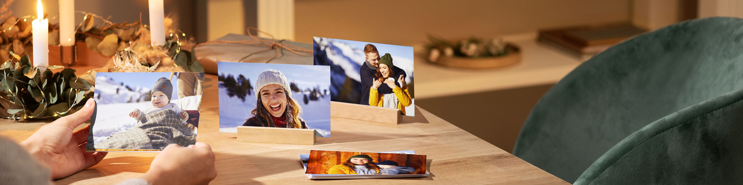 A person holds photo cards with holiday memories in hands, placed on a table.