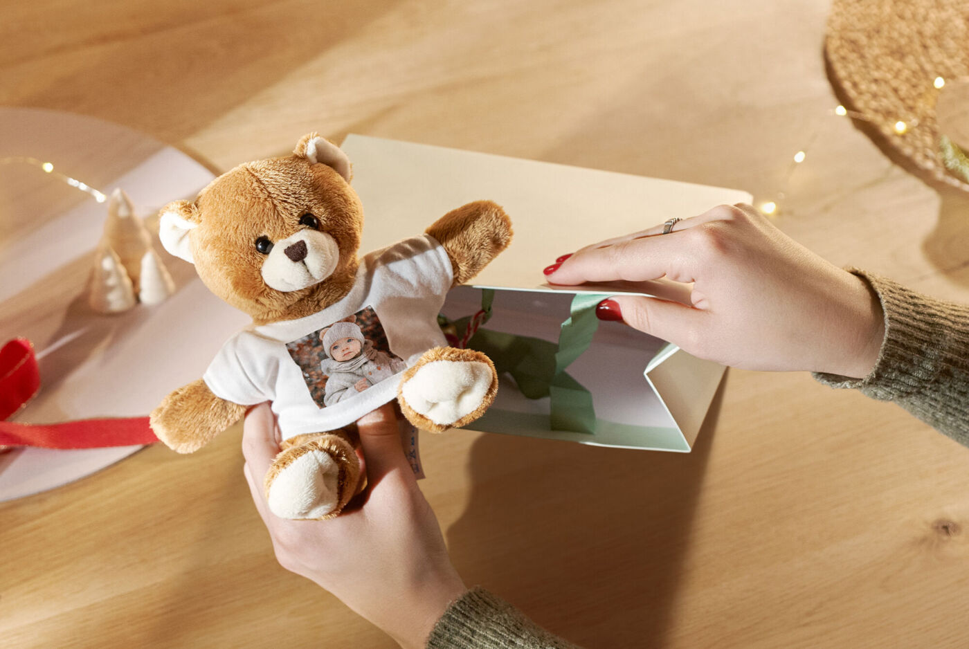 A cute teddy bear with a photo on his t-shirt, lovingly taken out of a gift box.